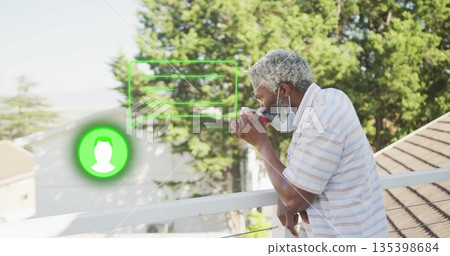 Leaning man sipping mug on balcony wearing surgical mask with green UI overlays, copy space 135398684