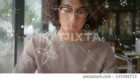 Researcher studying molecular graphics at cafe table near glass door, with glasses and ribbed shirt Researcher studying molecular graphics at cafe table near glass door, with glasses and ribbed shirt 135398713