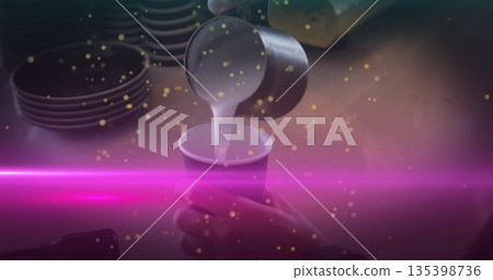 Pouring barista hand guiding metal pitcher filling paper cup at cafe counter, with neon pink light 135398736