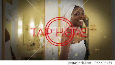 Woman in towel wrap smiling at camera in bathroom vanity, with orchid and TAP HERE graphic 135398764