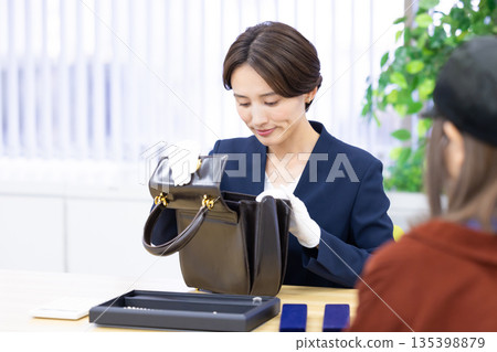 一位女士在採購公司的櫃檯評估一件商品 一位女士在採購公司的櫃檯評估一件商品 135398879