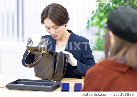 A woman assessing an item at a purchasing company's counter A woman assessing an item at a purchasing company's counter 135398880