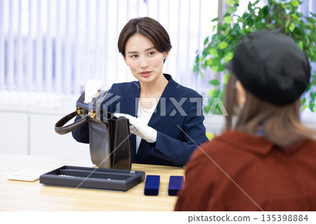 A woman assessing an item at a purchasing company's counter A woman assessing an item at a purchasing company's counter 135398884
