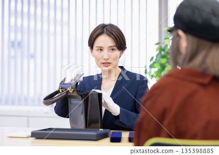 一位女士在採購公司的櫃檯評估一件商品 135398885