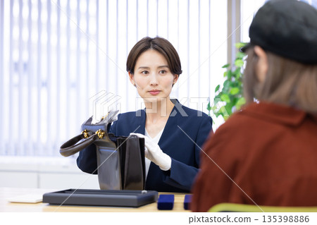 A woman assessing an item at a purchasing company's counter 135398886