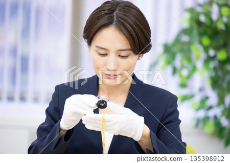 A woman assessing an item at a purchasing company's counter 135398912