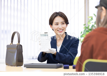 A woman assessing an item at a purchasing company's counter 135398918