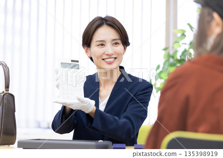 一位女士在採購公司的櫃檯評估一件商品 135398919