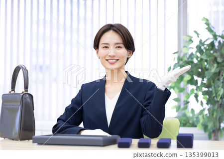 A woman assessing an item at a purchasing company's counter 135399013