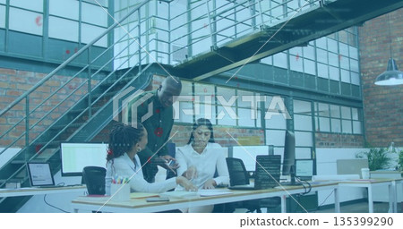 Reviewing papers three coworkers in business attire leaning over desk in loft office, with laptops Reviewing papers three coworkers in business attire leaning over desk in loft office, with laptops 135399290