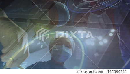Operating scrub-clad surgeon guiding team in operating room, surgical light, holograms and scalpel Operating scrub-clad surgeon guiding team in operating room, surgical light, holograms and scalpel 135399311