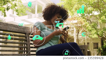 Using smartphone, woman interacting on wooden bench under pergola in garden, with digital eco icons Using smartphone, woman interacting on wooden bench under pergola in garden, with digital eco icons 135399428