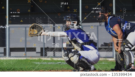 Squatting female catcher extending glove at ballpark, with teammate watching and digital overlays Squatting female catcher extending glove at ballpark, with teammate watching and digital overlays 135399434
