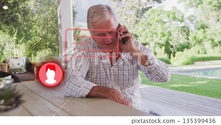 Talking man wearing checkered shirt holding smartphone on home patio, with digital overlay graphic 135399436