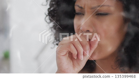 Holding hand to mouth, woman coughing behind dotted mesh panel in bright room, with blurred plant 135399468