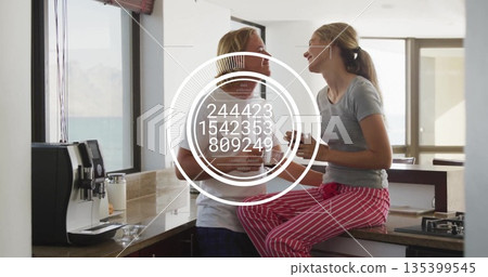Sharing coffee couple wearing pajamas holding mugs and talking in kitchen, with espresso machine Sharing coffee couple wearing pajamas holding mugs and talking in kitchen, with espresso machine 135399545
