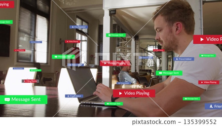 Typing man in white T-shirt working on laptop at table in living room, with floating labels 135399552