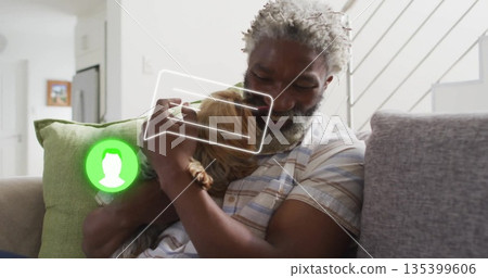 Smiling senior man wearing shirt holding long-haired dog on couch in living room, with chat overlay Smiling senior man wearing shirt holding long-haired dog on couch in living room, with chat overlay 135399606