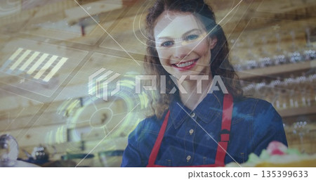 Smiling barista woman standing behind counter at cafe bakery, with pastry and holographic interface Smiling barista woman standing behind counter at cafe bakery, with pastry and holographic interface 135399633