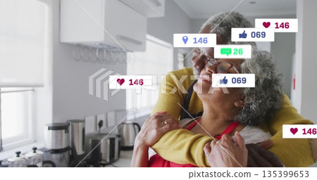 Embracing couple wearing red apron, yellow sweater in kitchen, with floating social icons, blender Embracing couple wearing red apron, yellow sweater in kitchen, with floating social icons, blender 135399653