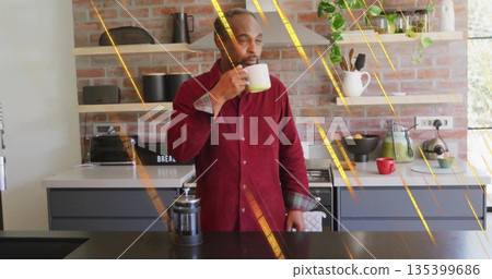 Sipping man wearing red shirt bringing white mug to lips at kitchen island, with French press 135399686