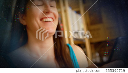 Smiling adult woman interacting with smartphone in home office with shelves and books, soft light Smiling adult woman interacting with smartphone in home office with shelves and books, soft light 135399719
