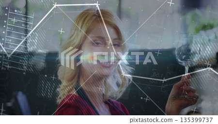 Raising adult woman smiling and toasting in lounge seating area, with wine glass and digital charts Raising adult woman smiling and toasting in lounge seating area, with wine glass and digital charts 135399737