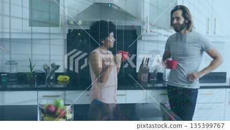 Chatting couple holding red mugs beside glossy kitchen island, with fruit bowl reflection 135399767