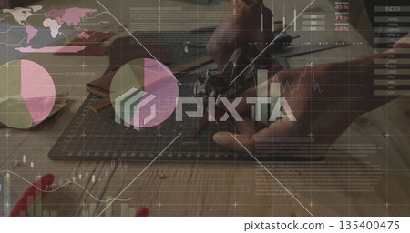 Trimming material with hand gripping craft knife on cutting mat in workshop, with smartphone Trimming material with hand gripping craft knife on cutting mat in workshop, with smartphone 135400475