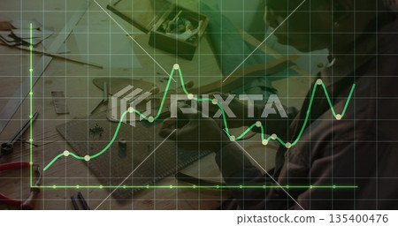 African American craftsman assembling components at bench, with cutting mat and line graph overlay African American craftsman assembling components at bench, with cutting mat and line graph overlay 135400476