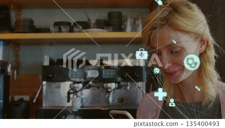 Checking barista interacting with smartphone and icons behind counter, espresso machine, copy space 135400493