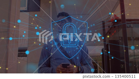 Holding smartphone man in sweater at office entry showing blue shield with padlock network overlay 135400511