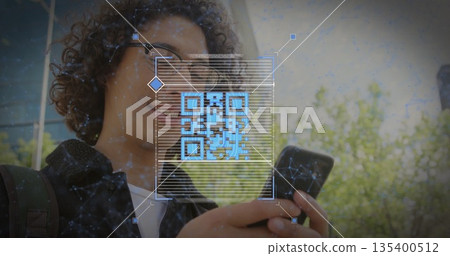 Scanning man in checkered shirt with backpack holding smartphone by facade, with QR code overlay 135400512