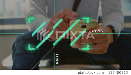 Businessman sitting on bench in lobby holding smartphone over shoulder bag with digital overlay 135400513