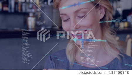 Smiling woman holding smartphone and viewing holographic code overlays at cafe counter, grey top 135400548