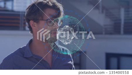 Exploring man wearing blue shirt and glasses using holographic sphere on rooftop, metal railing 135400558
