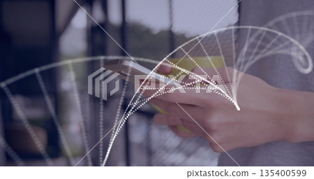 Holding silver smartphone while displaying white dotted arc on balcony railing overlooking greenery 135400599