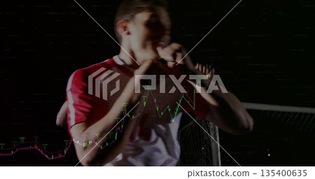 Male player in red-and-white jersey standing in dim arena with soccer net and financial line chart 135400635