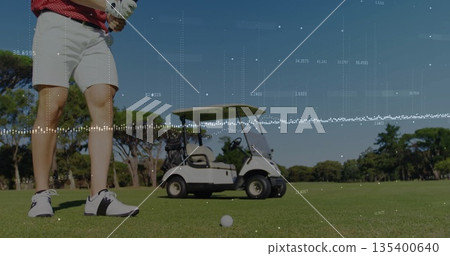 Gripping club golfer wearing red polo shirt, shorts on fairway, with golf ball, cart, copy space 135400640