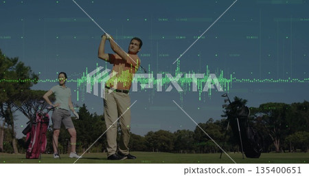 Mature couple swinging club at ball on fairway, with audio waveform overlay and two golf bags 135400651