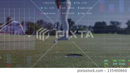 Lining up golfer in sportswear putting ball toward hole on green, with translucent financial charts 135400660
