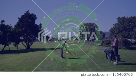 Swinging golfer hitting golf ball on tee box, friend standing next to golf bag, translucent overlay 135400766