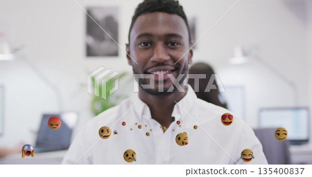 Standing smiling office worker wearing white shirt in modern open-plan office, with floating emojis Standing smiling office worker wearing white shirt in modern open-plan office, with floating emojis 135400837