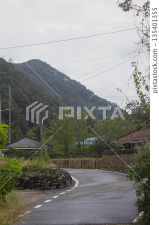 This is a rural road scene on a cloudy day. This is a rural road scene on a cloudy day. 135401355