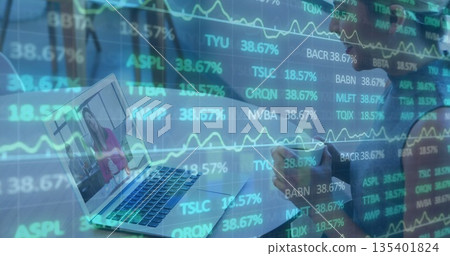 Woman in striped top writing notes at desk, with laptop showing colleague, overlaid charts Woman in striped top writing notes at desk, with laptop showing colleague, overlaid charts 135401824