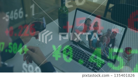 Holding wine glass, seated person watching family call on laptop at table, with wine bottle, ticker Holding wine glass, seated person watching family call on laptop at table, with wine bottle, ticker 135401826