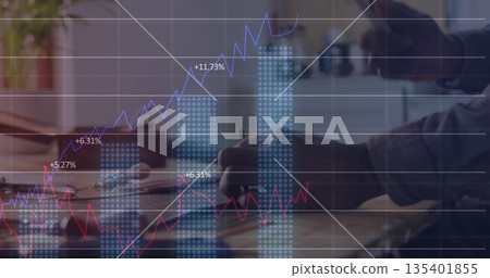 African American man penning in notebook at office desk with laptop, mug, plant displaying charts 135401855