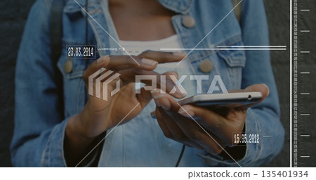 Woman wearing denim jacket tapping smartphone screen against dark stone wall, with data overlays Woman wearing denim jacket tapping smartphone screen against dark stone wall, with data overlays 135401934