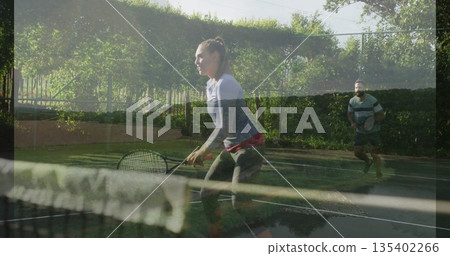 Holding tennis racket, woman in sportswear preparing return on outdoor court, with net and fence Holding tennis racket, woman in sportswear preparing return on outdoor court, with net and fence 135402266