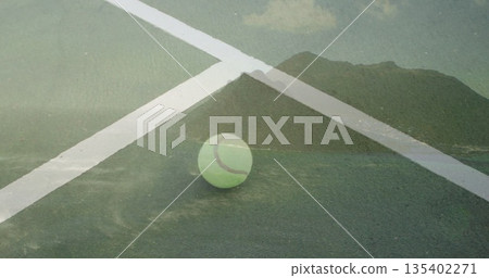 Sitting neon-green tennis ball on hard court, with white boundary lines and mountain-lake overlay 135402271